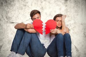 38515503 - young couple holding broken heart against grey background